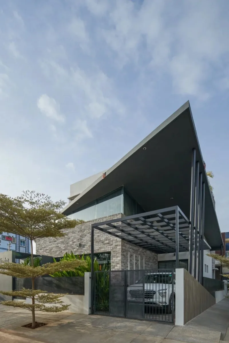 Low-angle view of a luxury house with a sharp soaring roof soffit and stone brick wall designed by architects in Bangalore