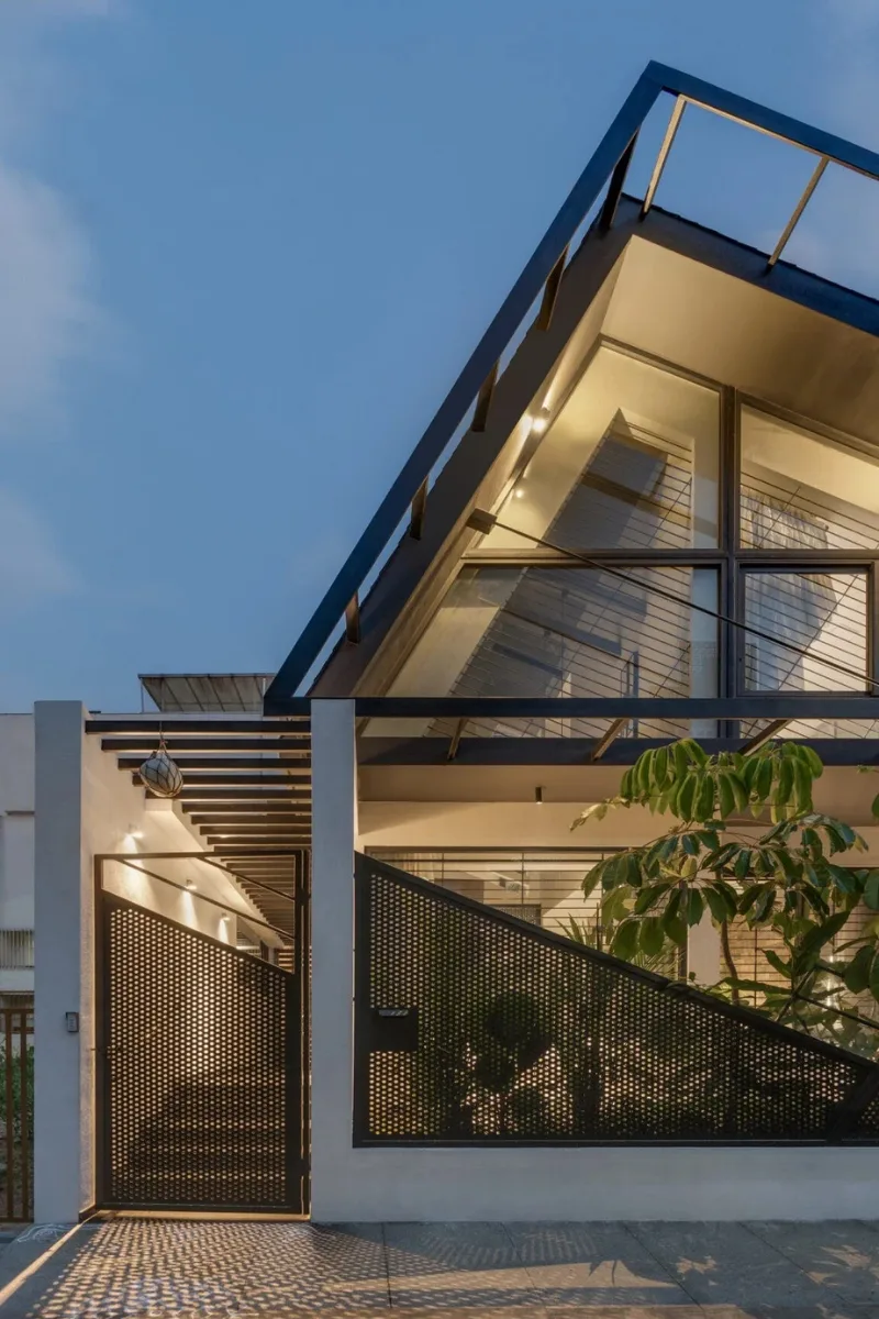 Contemporary house entrance featuring a triangular steel roof frame and perforated metal gate designed by architects in Bangalore