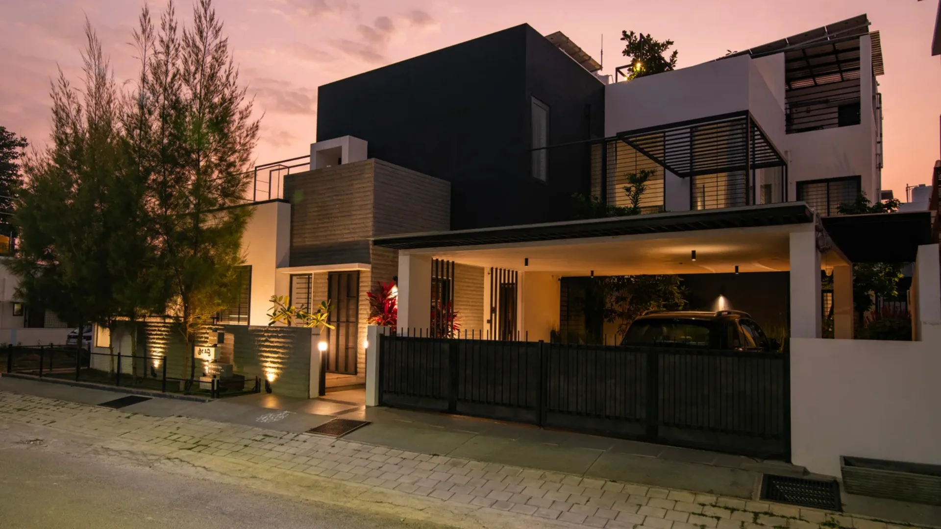 Contemporary multi-story villa with warm ambient exterior lighting and dark cubic facade designed by architects in Bangalore