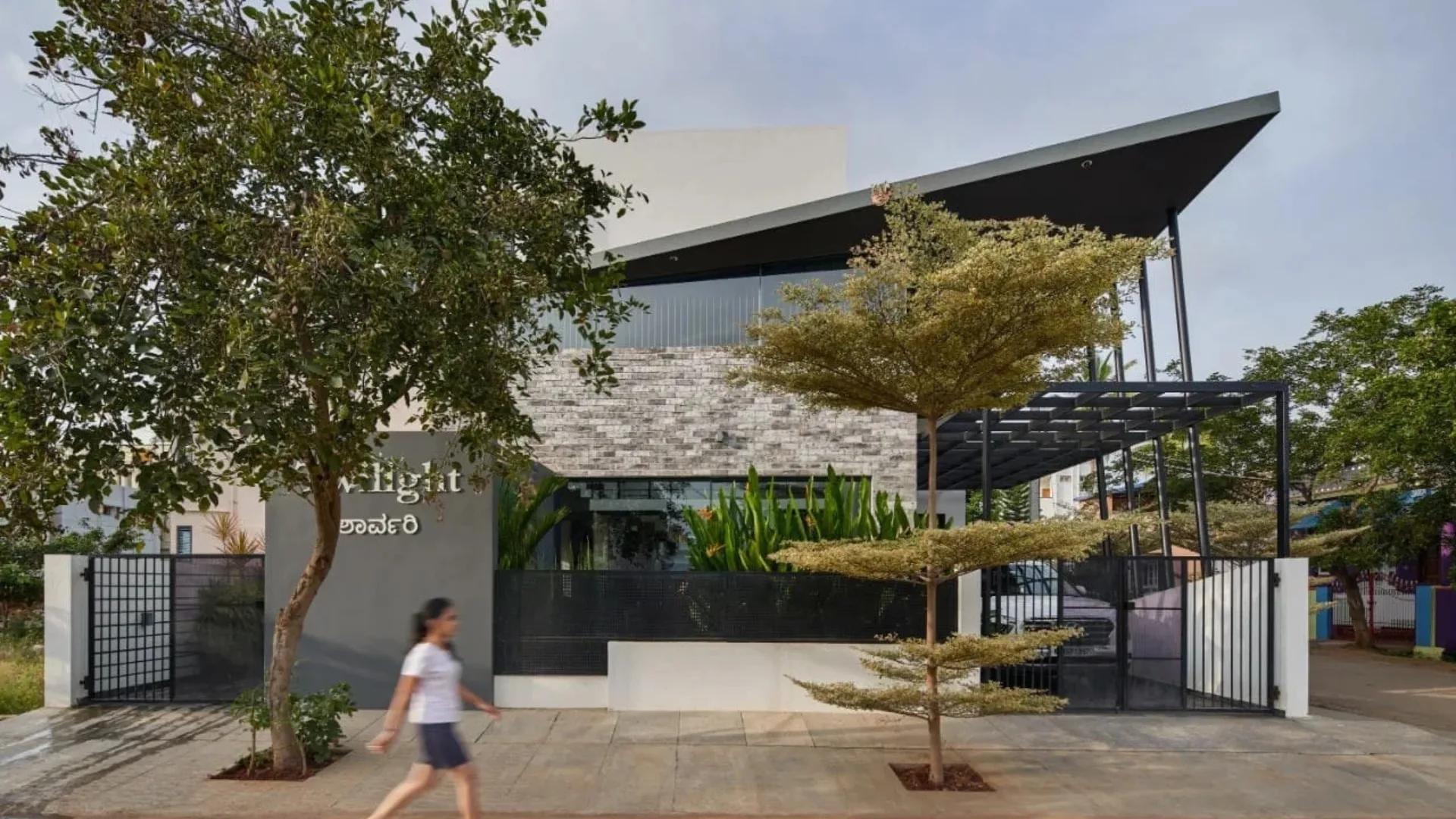 Modern home exterior with dynamic upward-sloping roofline and stone cladding designed by architects in Bangalore
